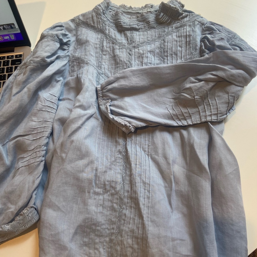 Light blue blouse. Light cotton. Cinched back. Lace detailed high neckline.